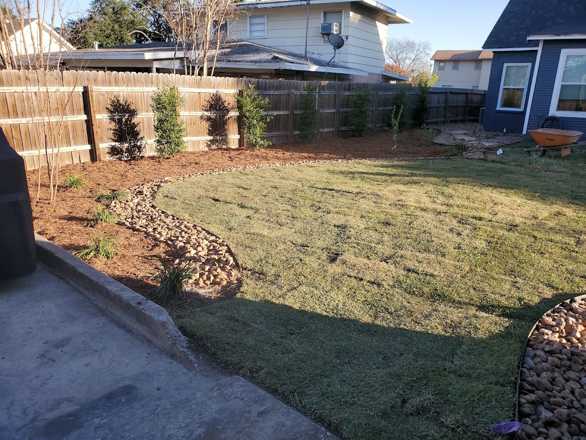Backyard transformation with mulch beds, shrubs, and stone drainage