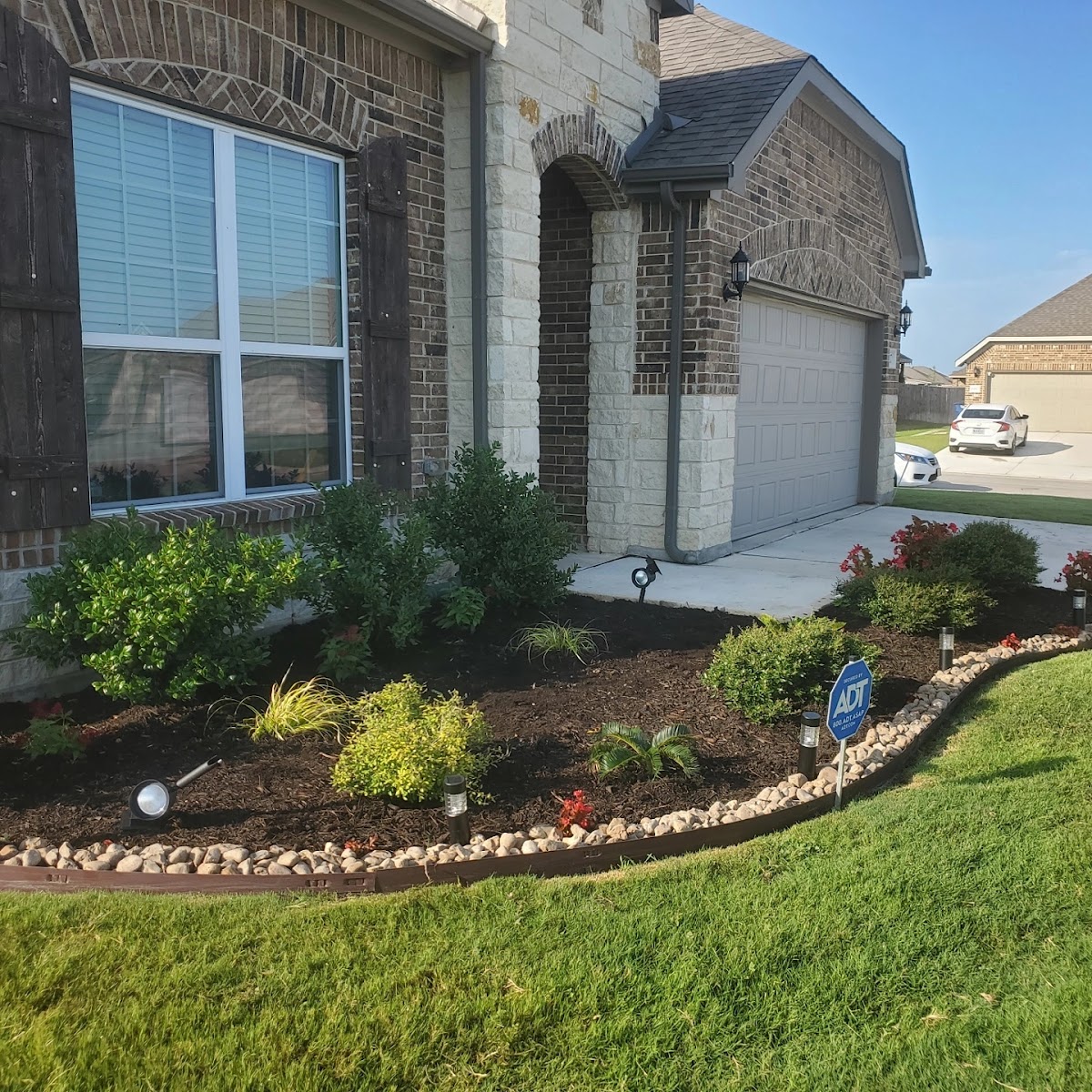 Professional front-yard mulch beds with landscape lighting